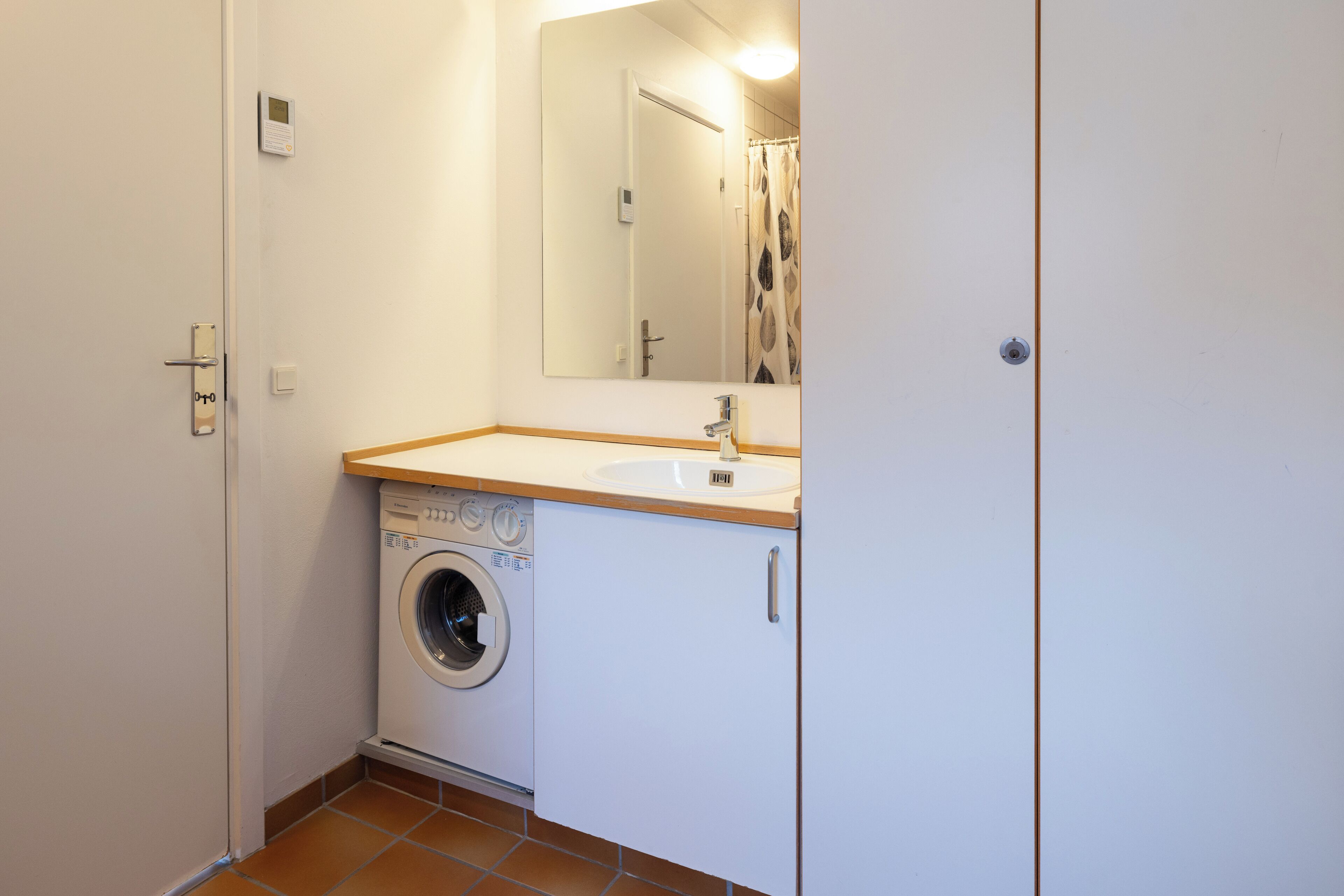 Un baño pequeño con lavadora, lavamanos y espejo.