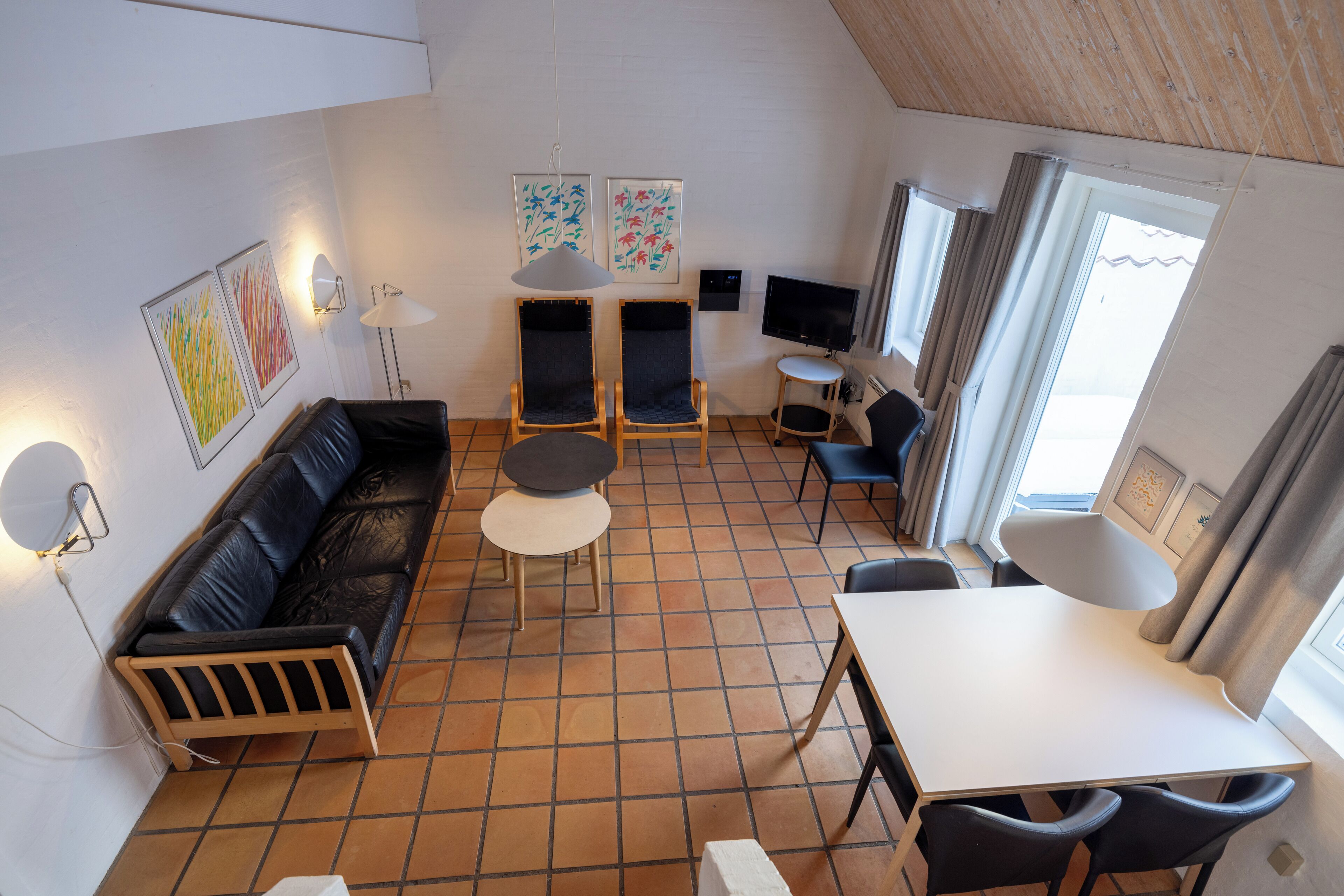 A compact living space with a sofa, two armchairs, a small table, and a TV.
