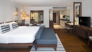 A modern hotel room with a large bed, a sofa, a desk, and a television. - Woodlands Suites Serviced Residences (Pattaya)