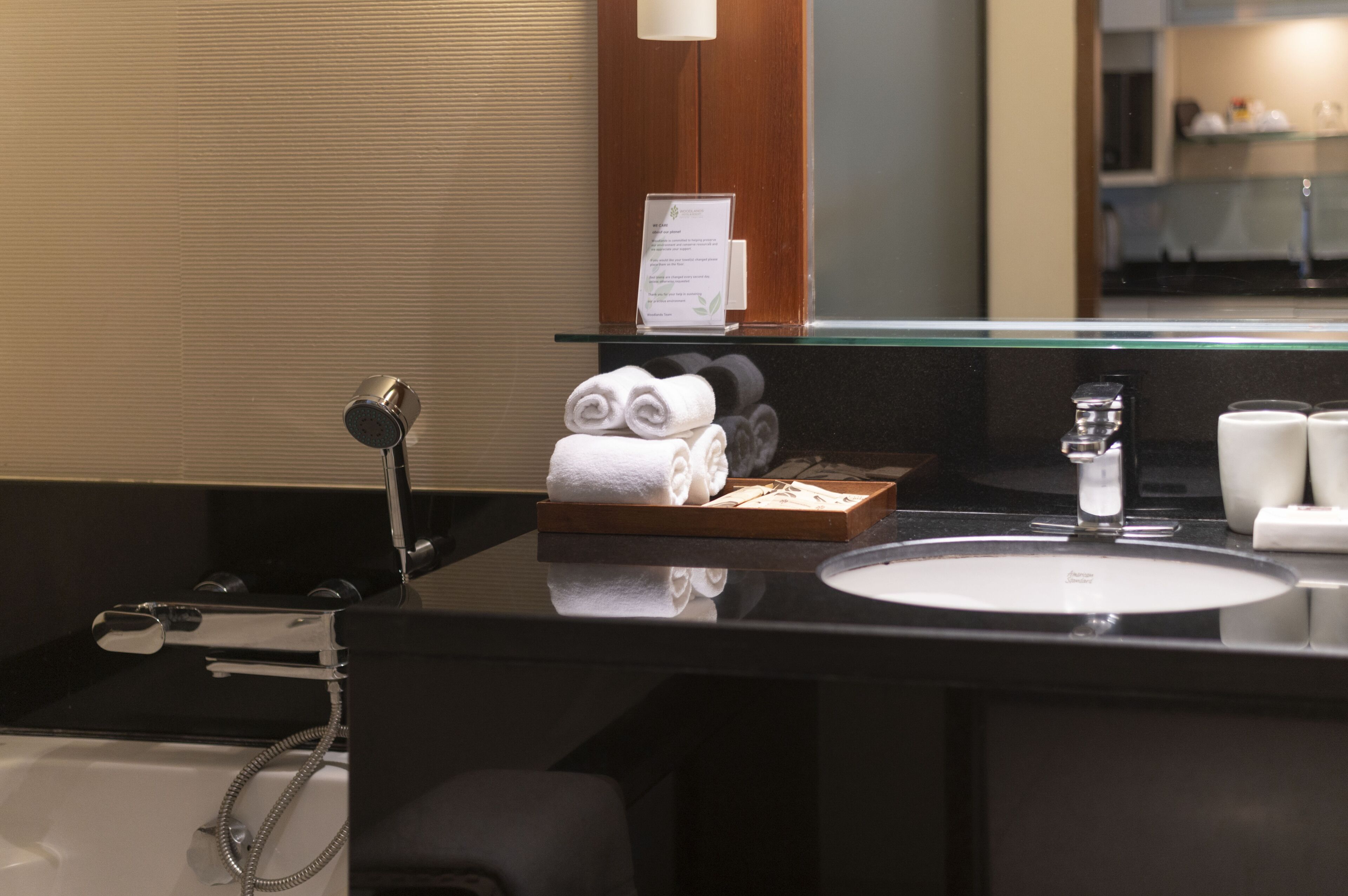 Een moderne badkamer met een zwart aanrecht, een witte wastafel en een douchecabine van glas.