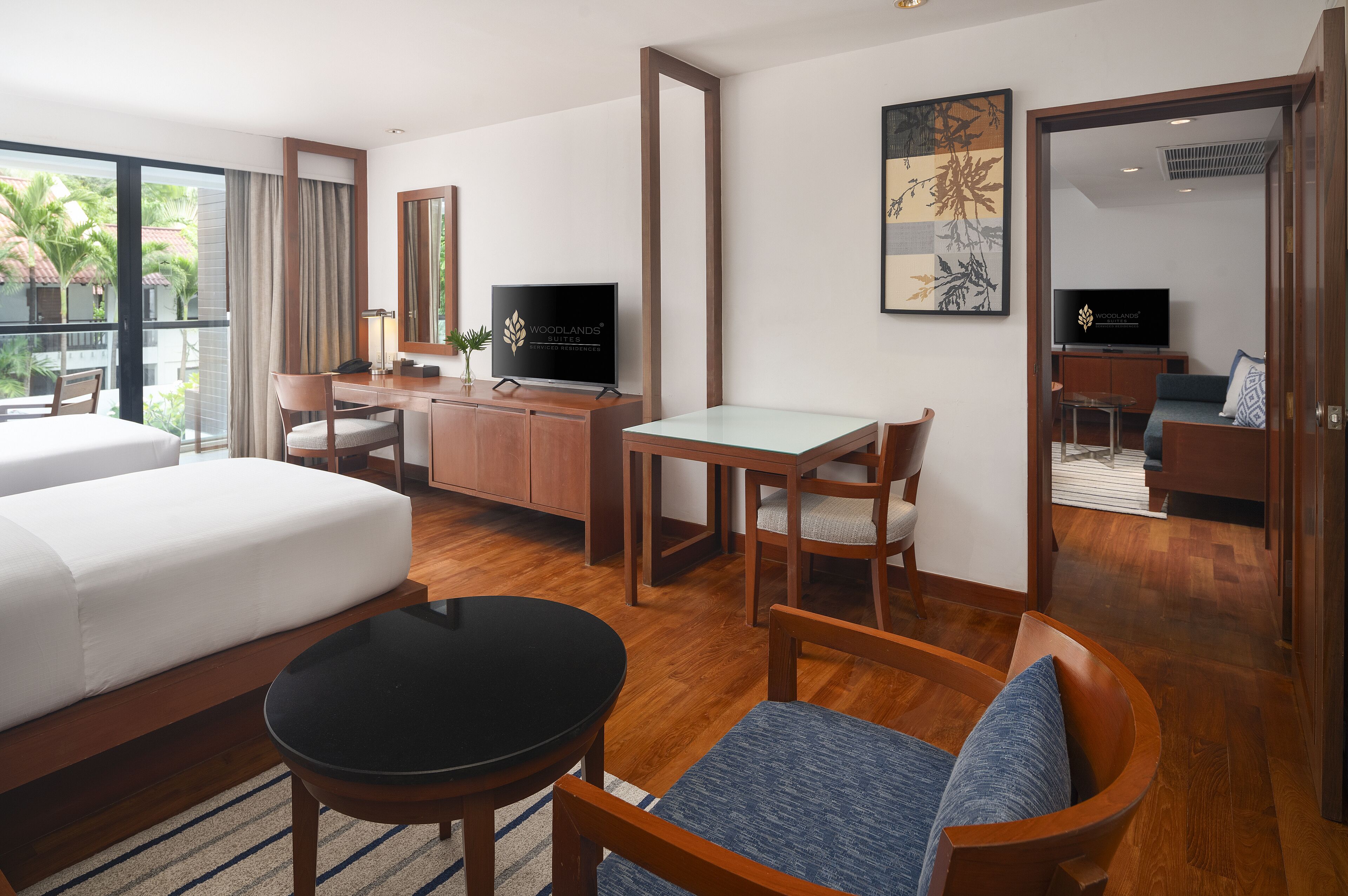 A hotel room with a bed, a desk, a TV, a dining table, and a sofa.