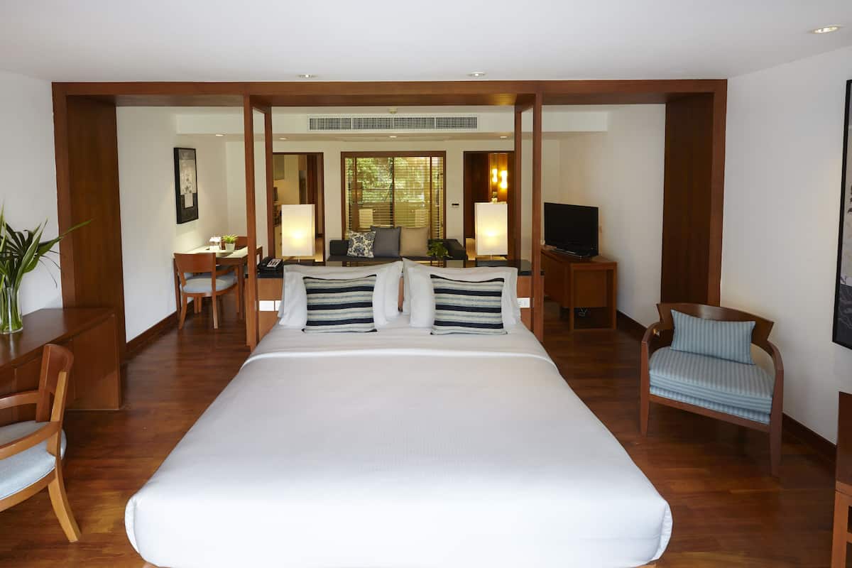 Hotelkamer met een groot bed, een bureau met stoel, een televisie en een zithoek met stoel en lamp.