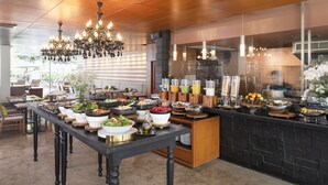 A buffet setup with various food items and a modern interior design. - Woodlands Suites Serviced Residences (Pattaya)