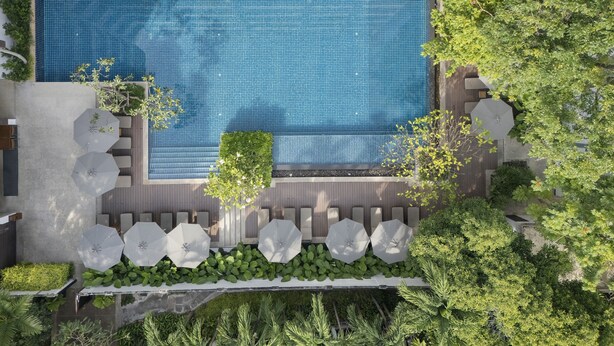 A rooftop pool with a tiled surface, surrounded by greenery and outdoor seating. - Woodlands Suites Serviced Residences (Pattaya)