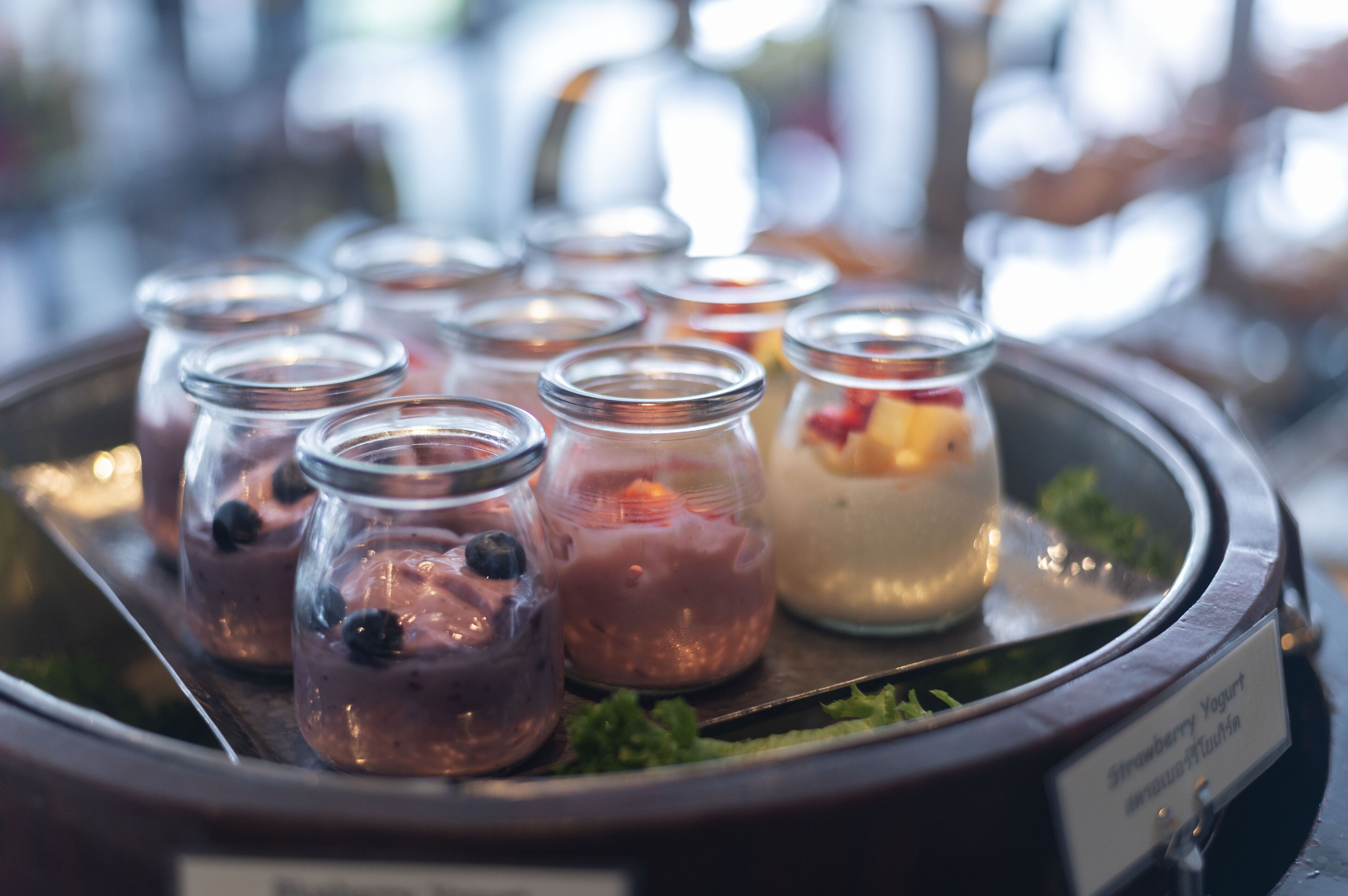 A tray with various jars of food, including a strawberry yogurt parfait.