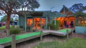 A rustic building with a wooden deck and a green artificial turf area. - Lake Hume Holiday Park (Bowna)