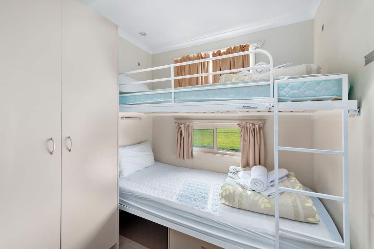 Habitación con literas, ventana, cortinas y armario.