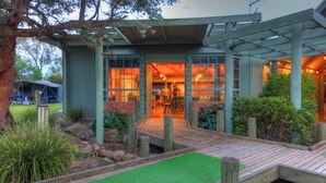 A modern building with a wooden deck, large windows, and a covered outdoor area. - Lake Hume Holiday Park (Bowna)