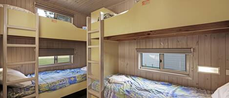 A bunk bed room with wooden walls and a window.