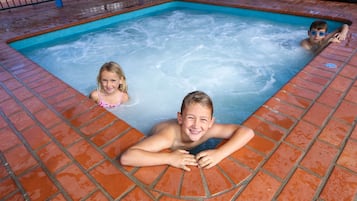 Una piscina con borde de azulejos y suelo de ladrillo.