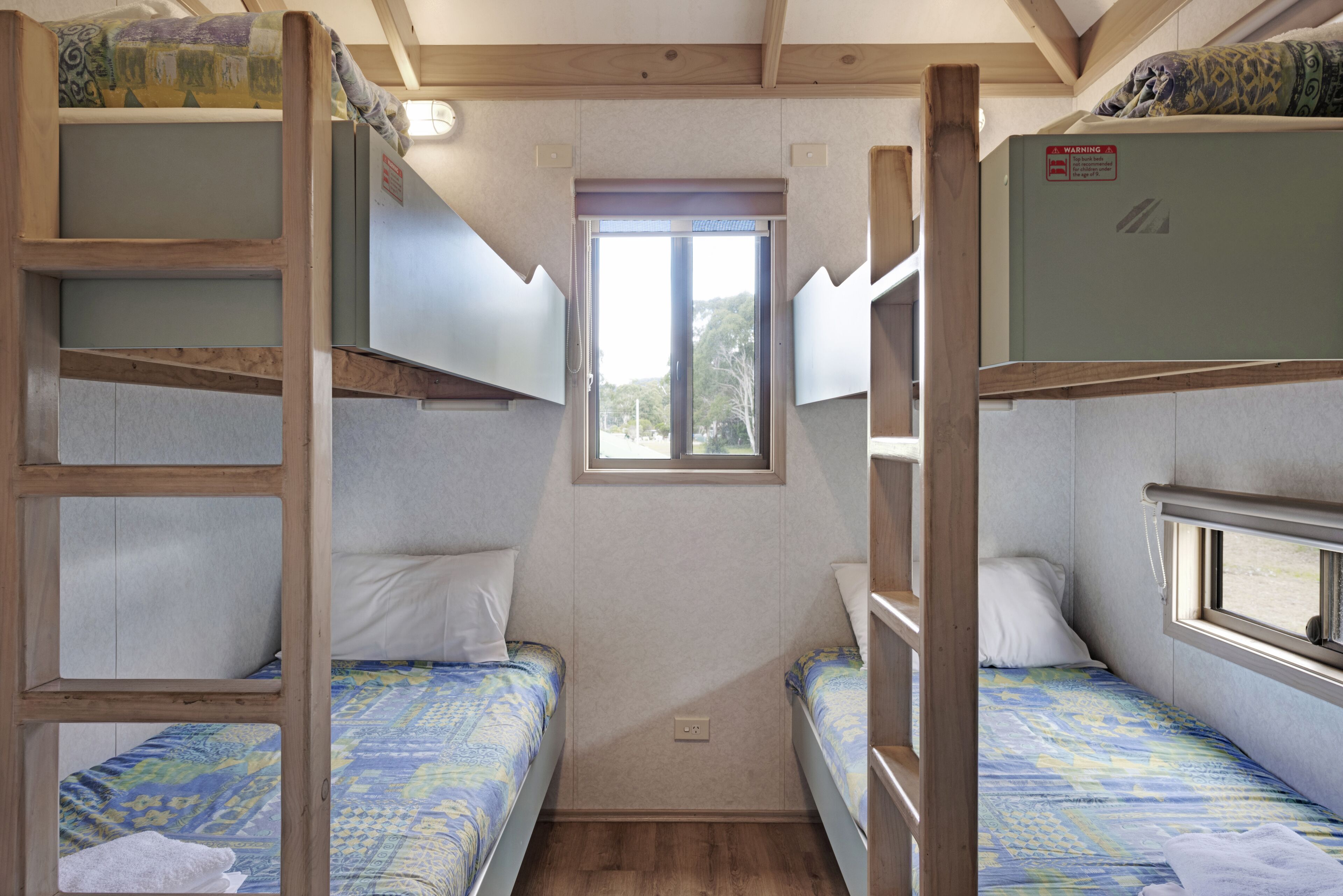 A compact room with bunk beds, a small window, and a door.