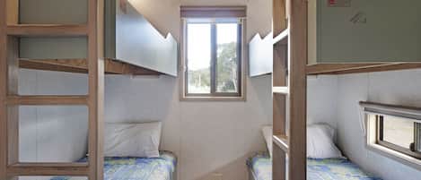 A compact room with bunk beds, a small window, and a door.