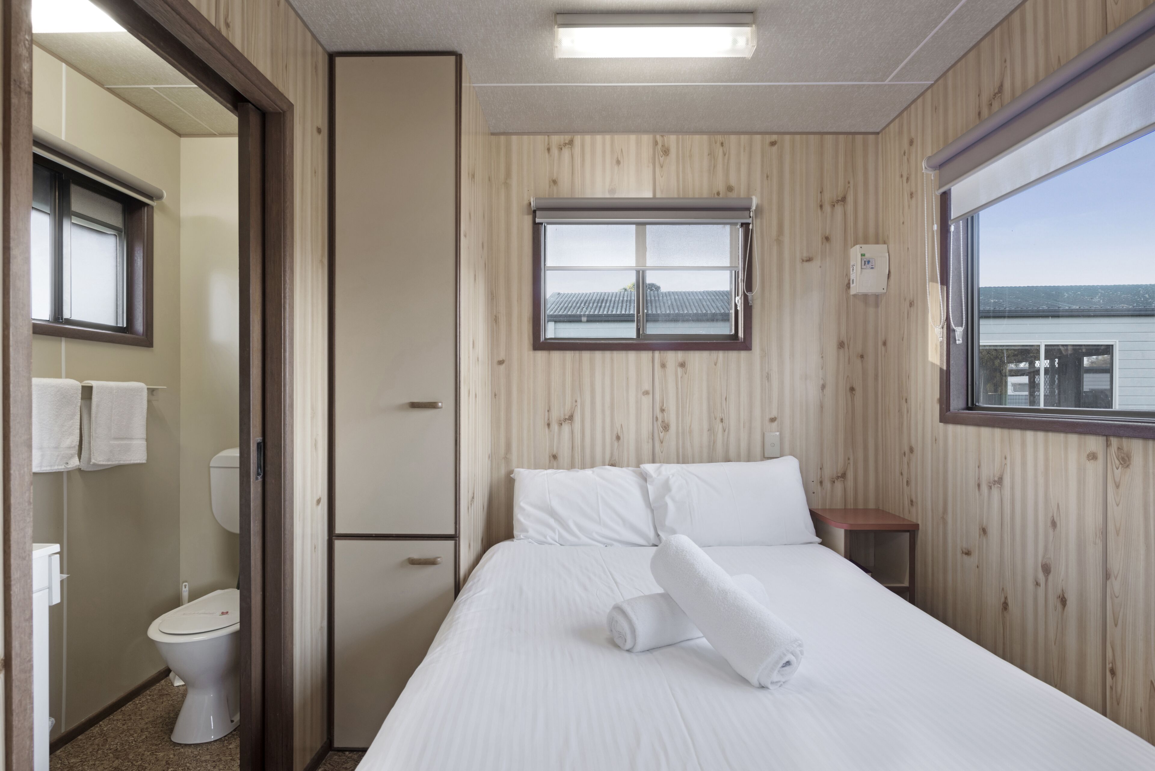 Habitación de hotel con cama, ventana con vistas, inodoro y espejo.