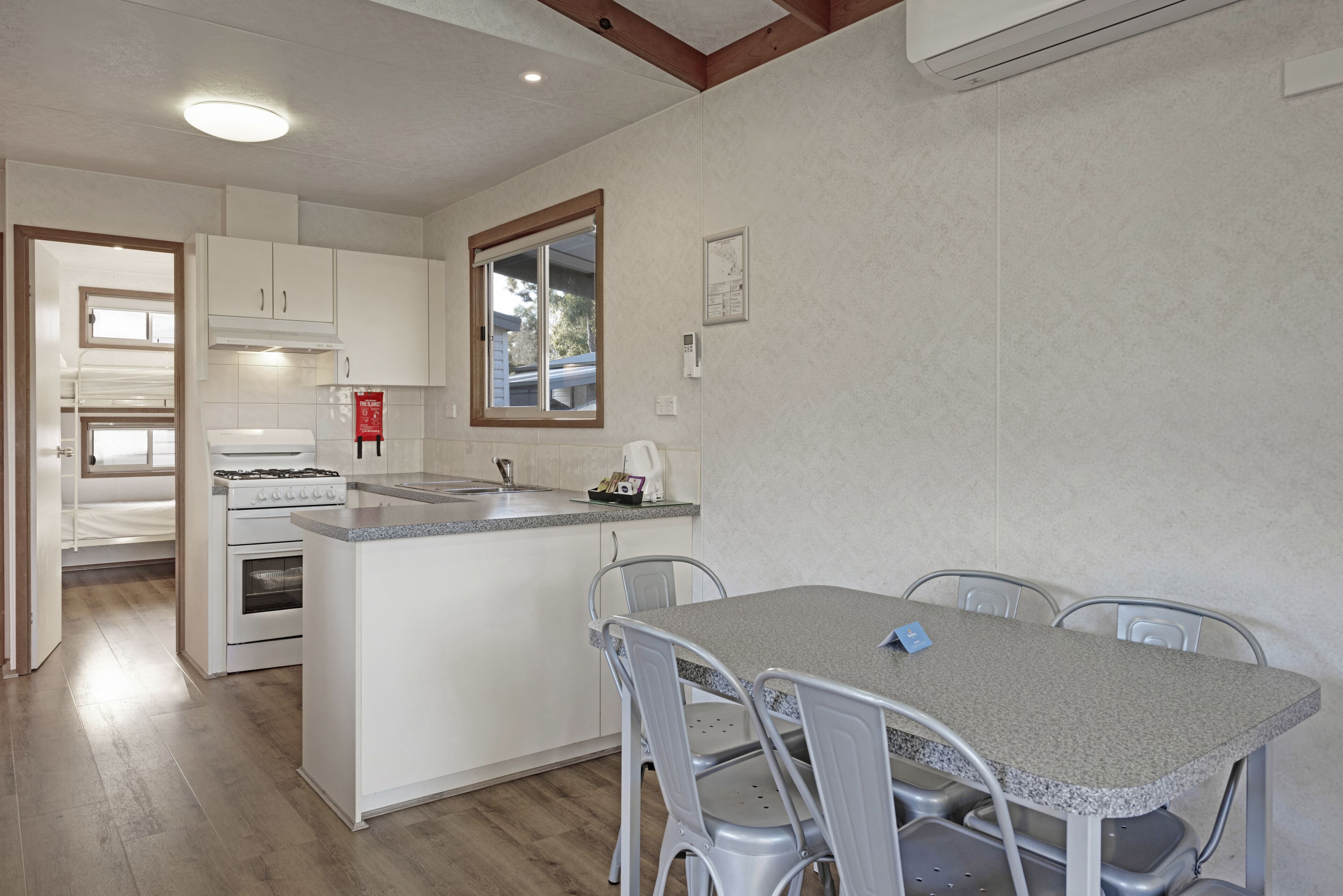 A compact kitchen with a central island, white cabinetry, and a dining area with metal chairs.