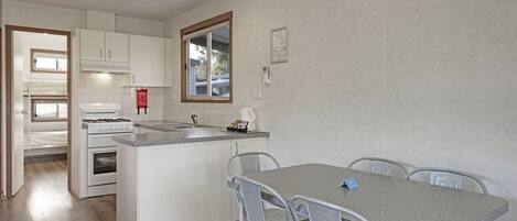 A compact kitchen with a central island, white cabinetry, and a dining area with metal chairs.