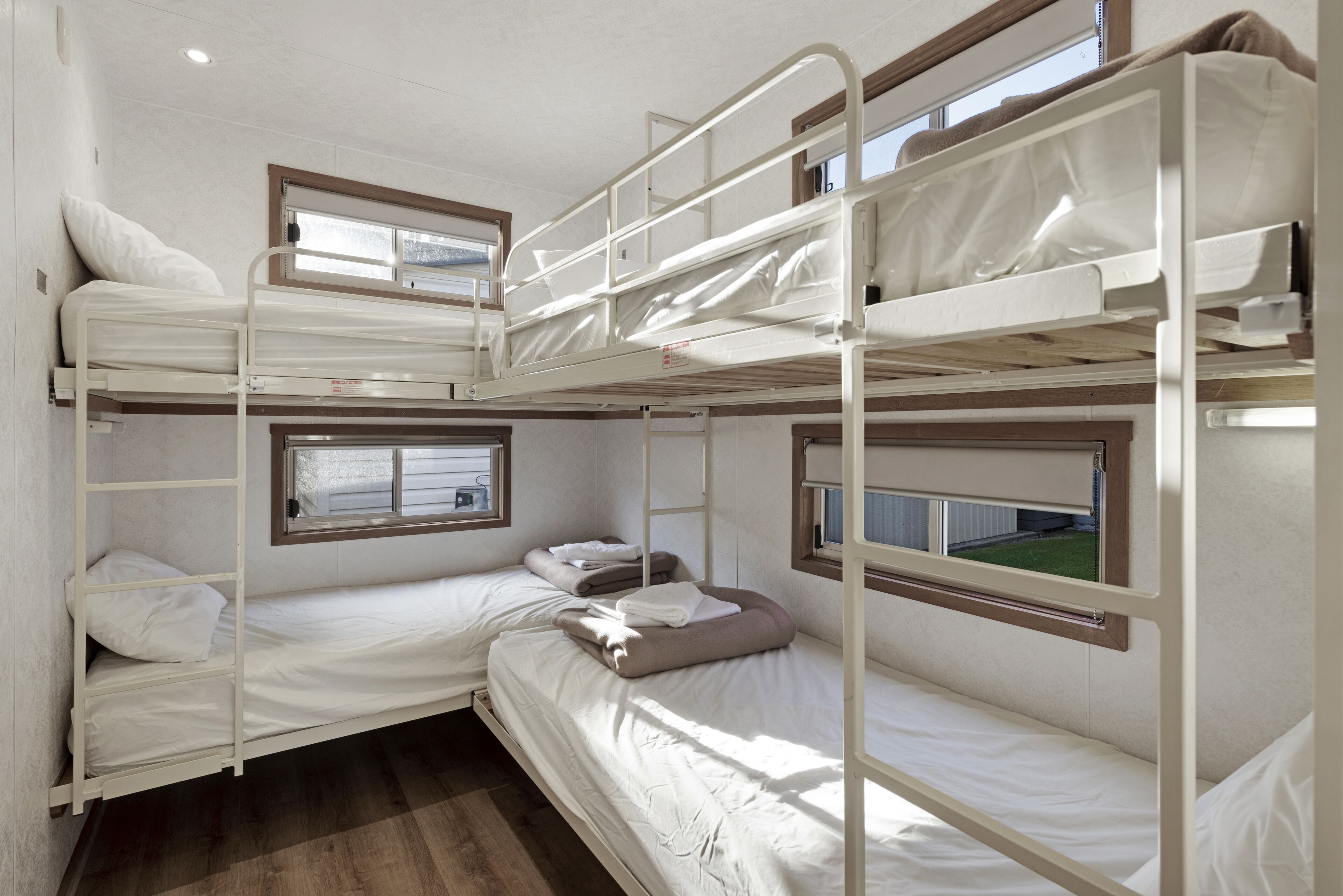 A bunk bed room with two beds, a window, and a door.