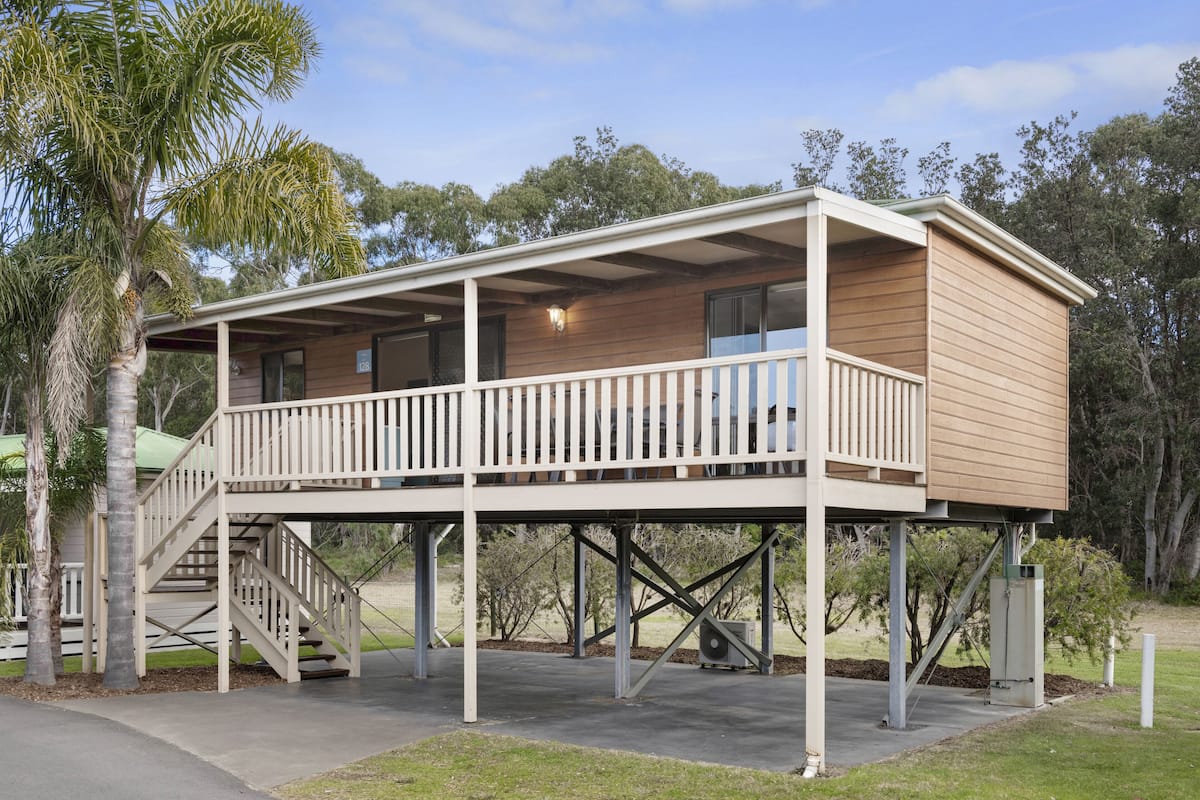 A two-story wooden building with a balcony, a staircase, and a small porch area.