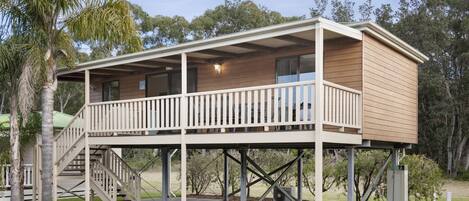 A two-story wooden building with a balcony, a staircase, and a small porch area.