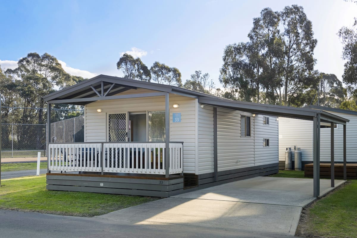 A mobile home with a fenced porch, a covered outdoor seating area, and a number sign indicating unit 33.