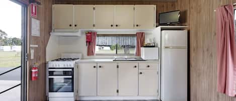 A compact kitchenette with a stove, oven, sink, and refrigerator.