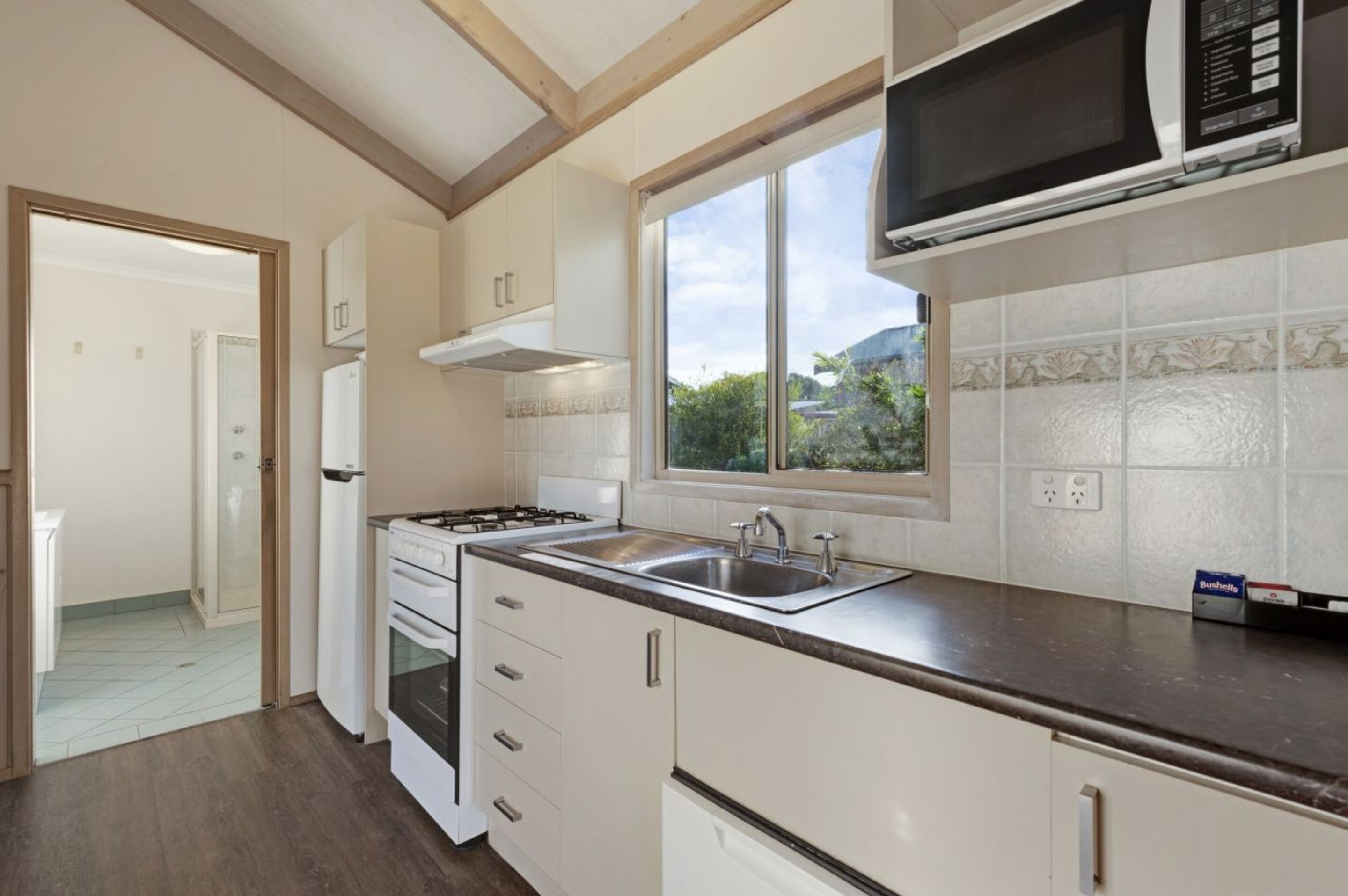 A kitchen with white cabinets, a stove, a sink, and a microwave.