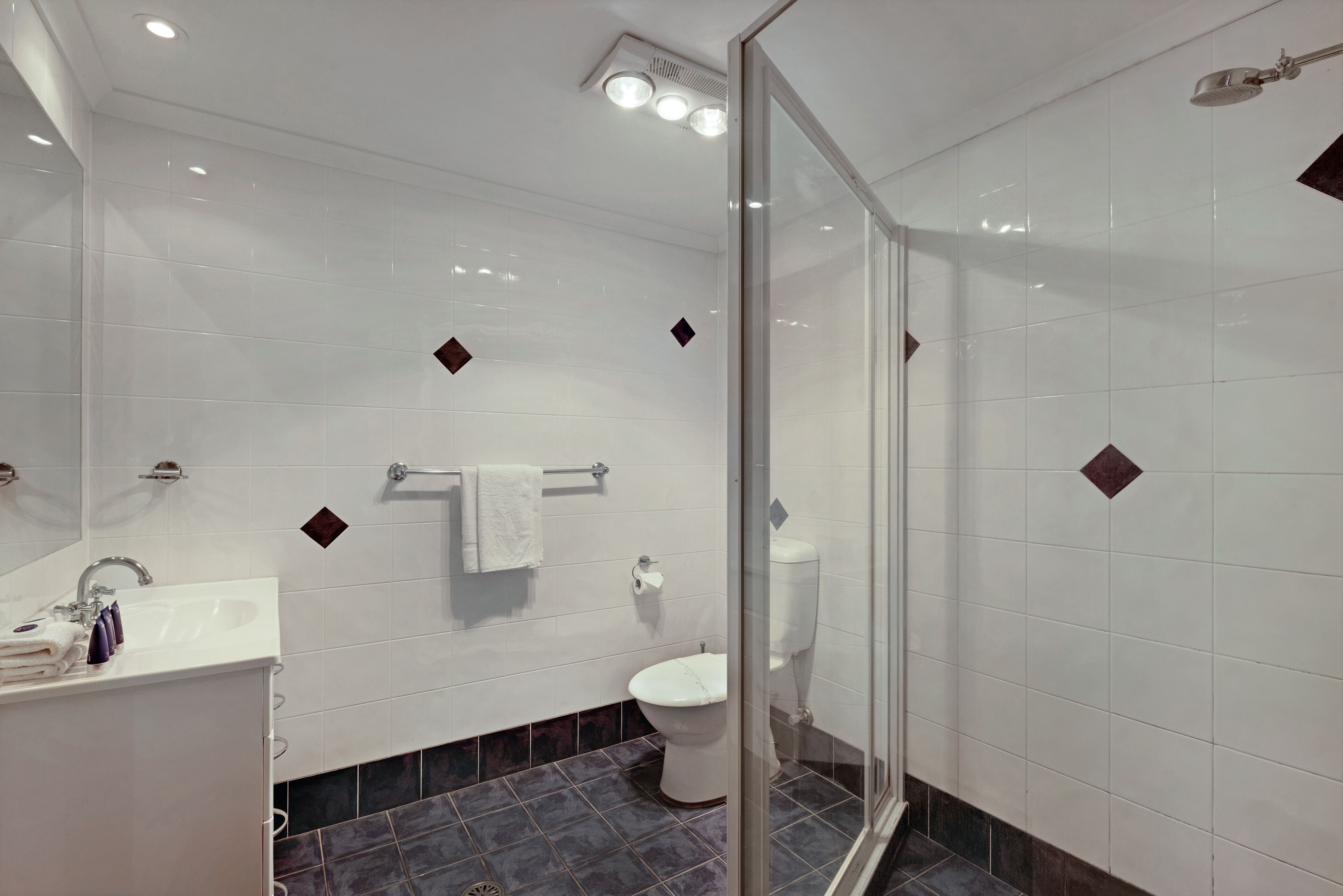 A modern bathroom with a glass-enclosed shower, a white sink, and a toilet.