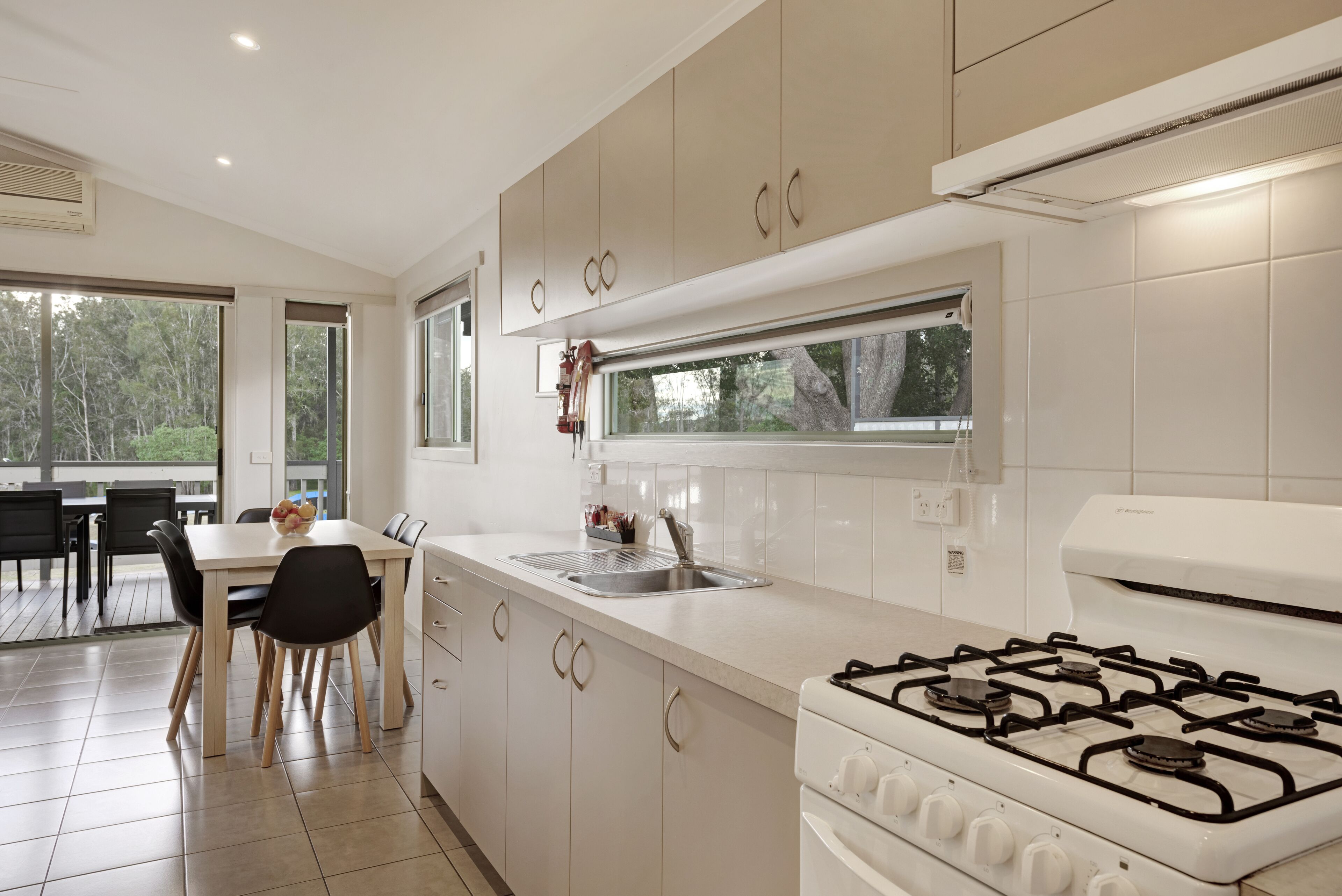 Een moderne keuken met een gasfornuis, een spoelbak en een eethoek met een tafel en stoelen.
