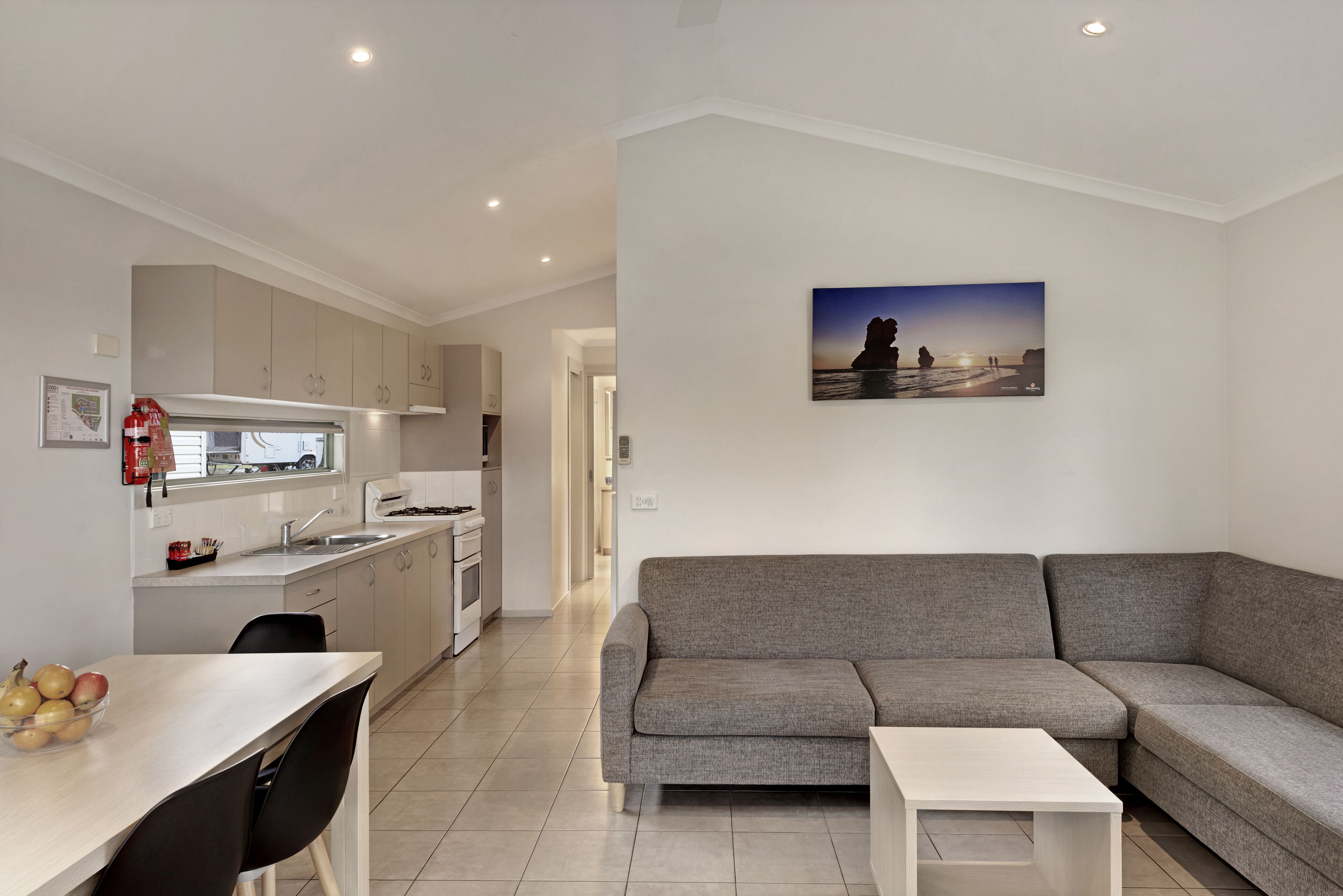 A modern kitchen with a dining area, a grey sofa, and a small table.