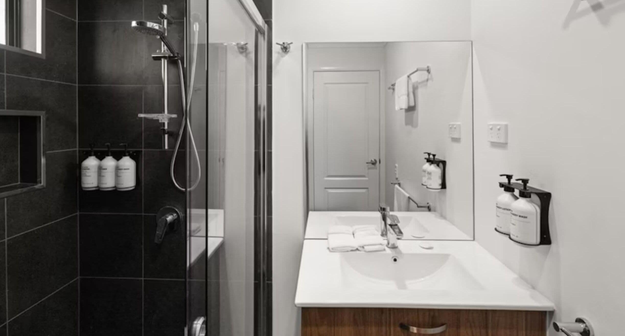 A modern bathroom with a glass-enclosed shower, a white sink, and a mirror.