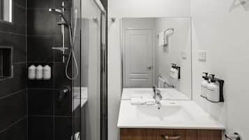 A modern bathroom with a glass-enclosed shower, a white sink, and a mirror.
