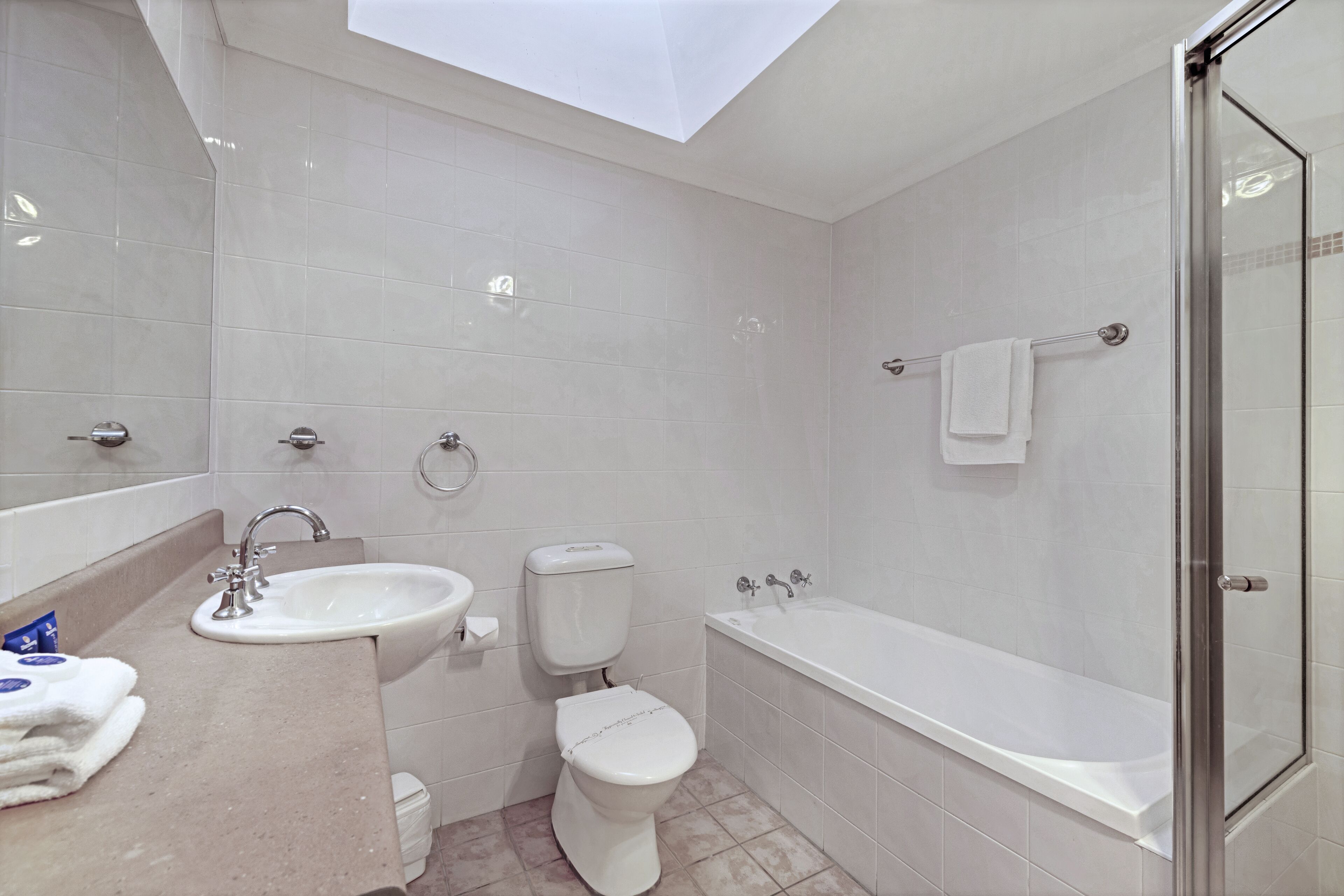 A modern bathroom with a skylight, a sink, toilet, and a bathtub.