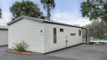 A single-story mobile home with a gabled roof, a small porch, and a number sign indicating unit 106.