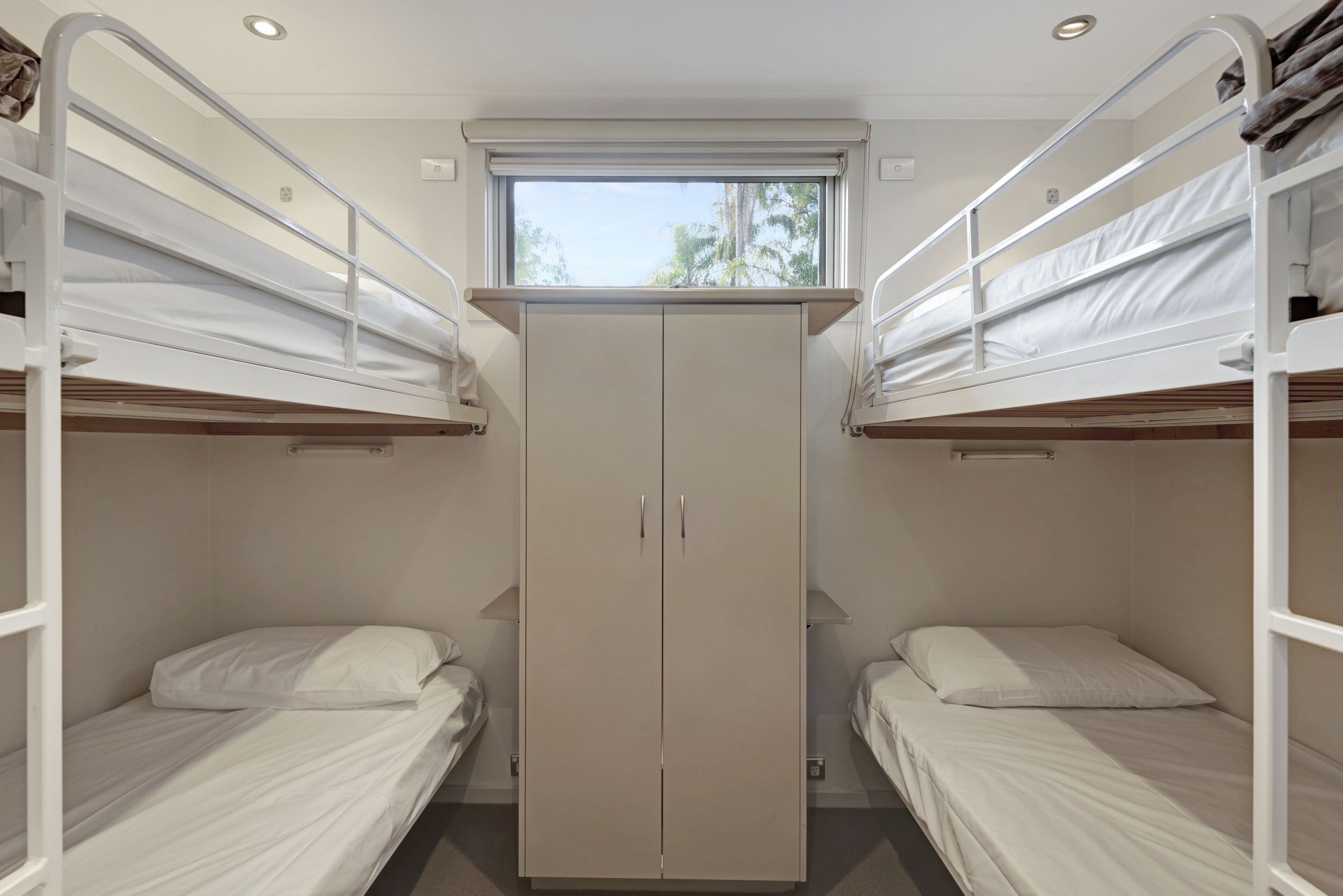 A room with two bunk beds, a wardrobe, and a window.