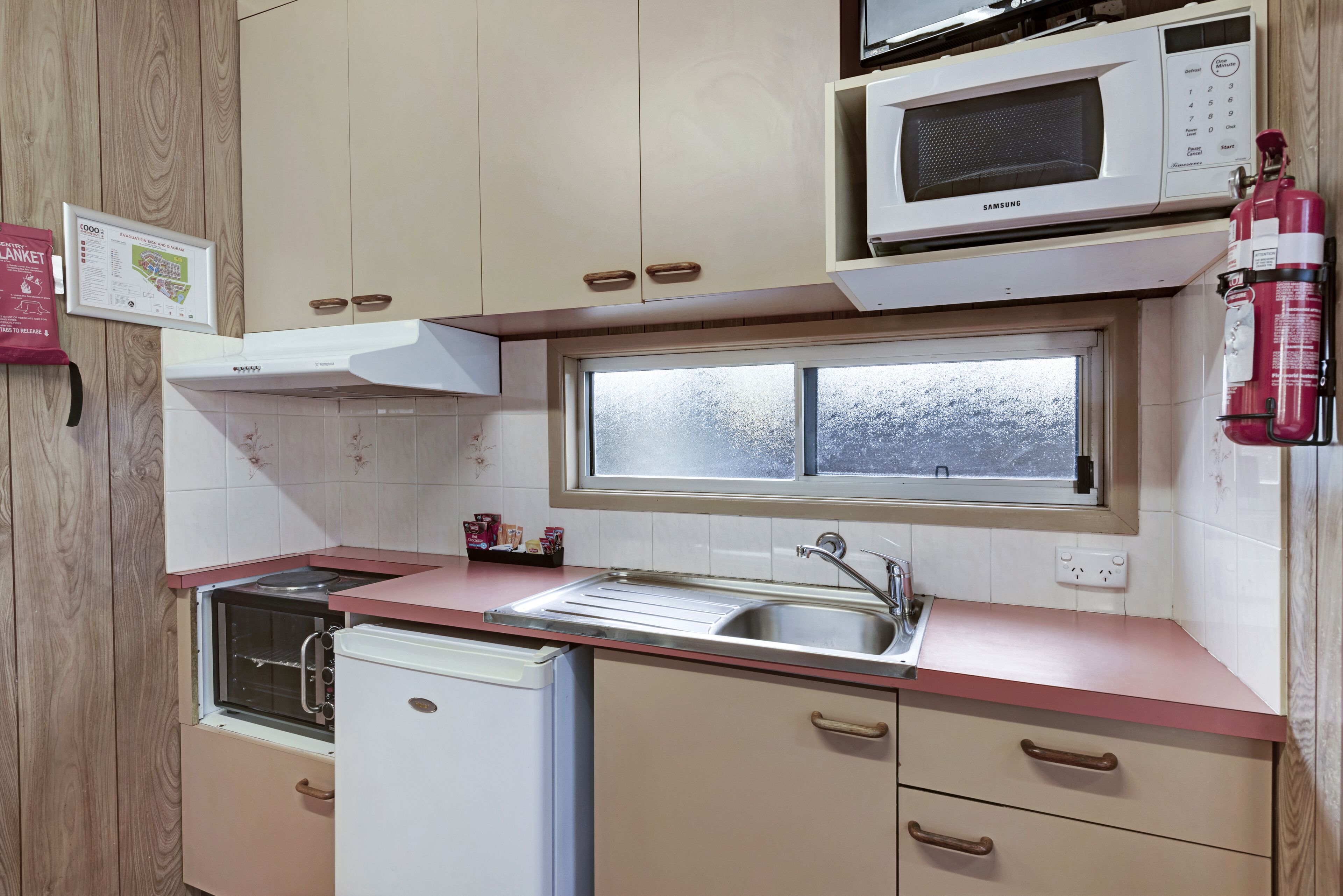 Una cocina con microondas, horno, pileta y ventana.