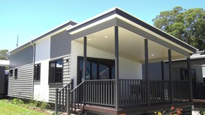 Une maison moderne à deux étages, dotée d’un porche couvert et d’un petit jardin à l’avant.