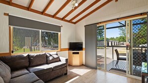 A modern living room with a sectional sofa, a flat-screen TV, and large sliding glass doors leading to an outdoor deck.