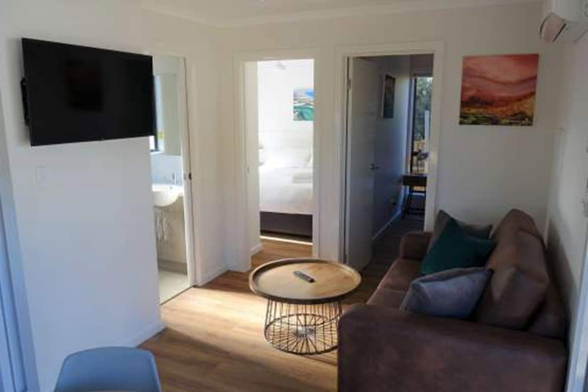 A modern living room with a sofa, a round coffee table, and a flat-screen TV mounted on the wall.