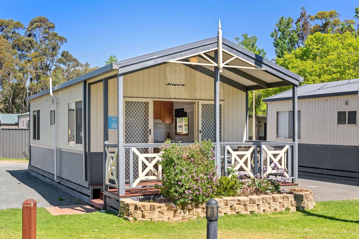 A mobile home with a covered porch, a small garden, and a number 38 sign.