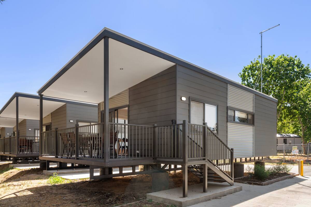 A modern single-story mobile home with a covered porch and a small deck area.