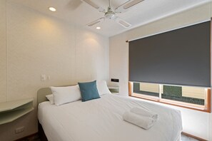 Relax in a serene space with a large bed, bedside table, and ceiling fan.