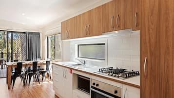 A modern kitchen with wooden cabinets, a gas stove, a built-in oven, and a large window.