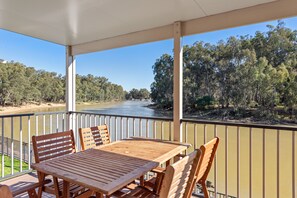 Enjoy a serene riverside view from this deck, surrounded by a dense forest.