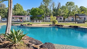 A swimming pool with lounge chairs, palm trees, and a clear blue sky.