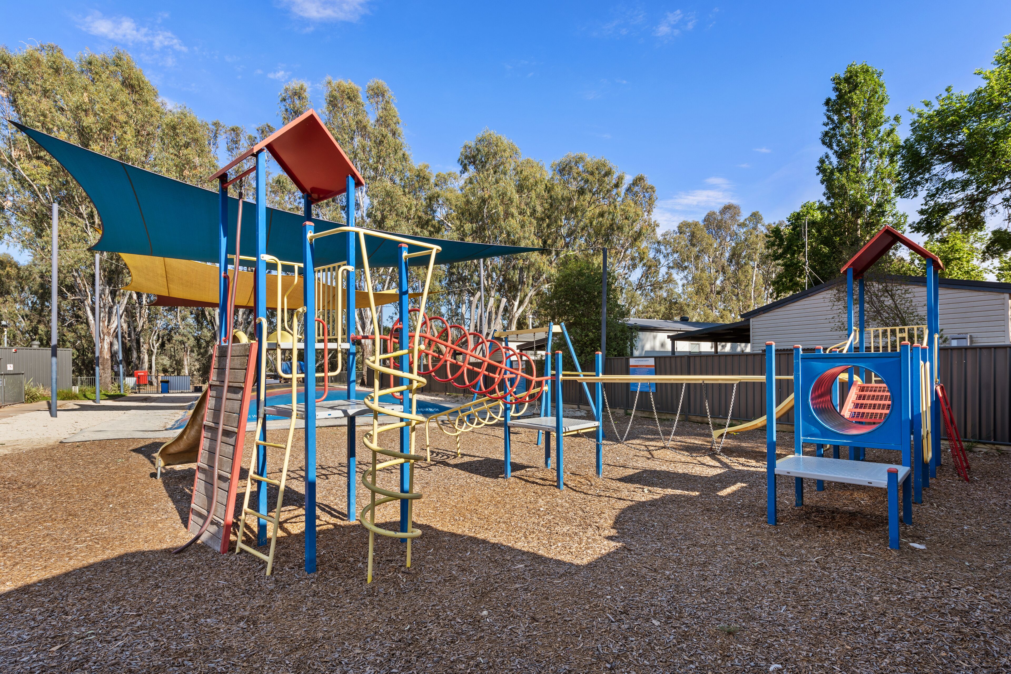 Un parque infantil con diversas estructuras de juego, como toboganes, escaleras de cuerda y un túnel.