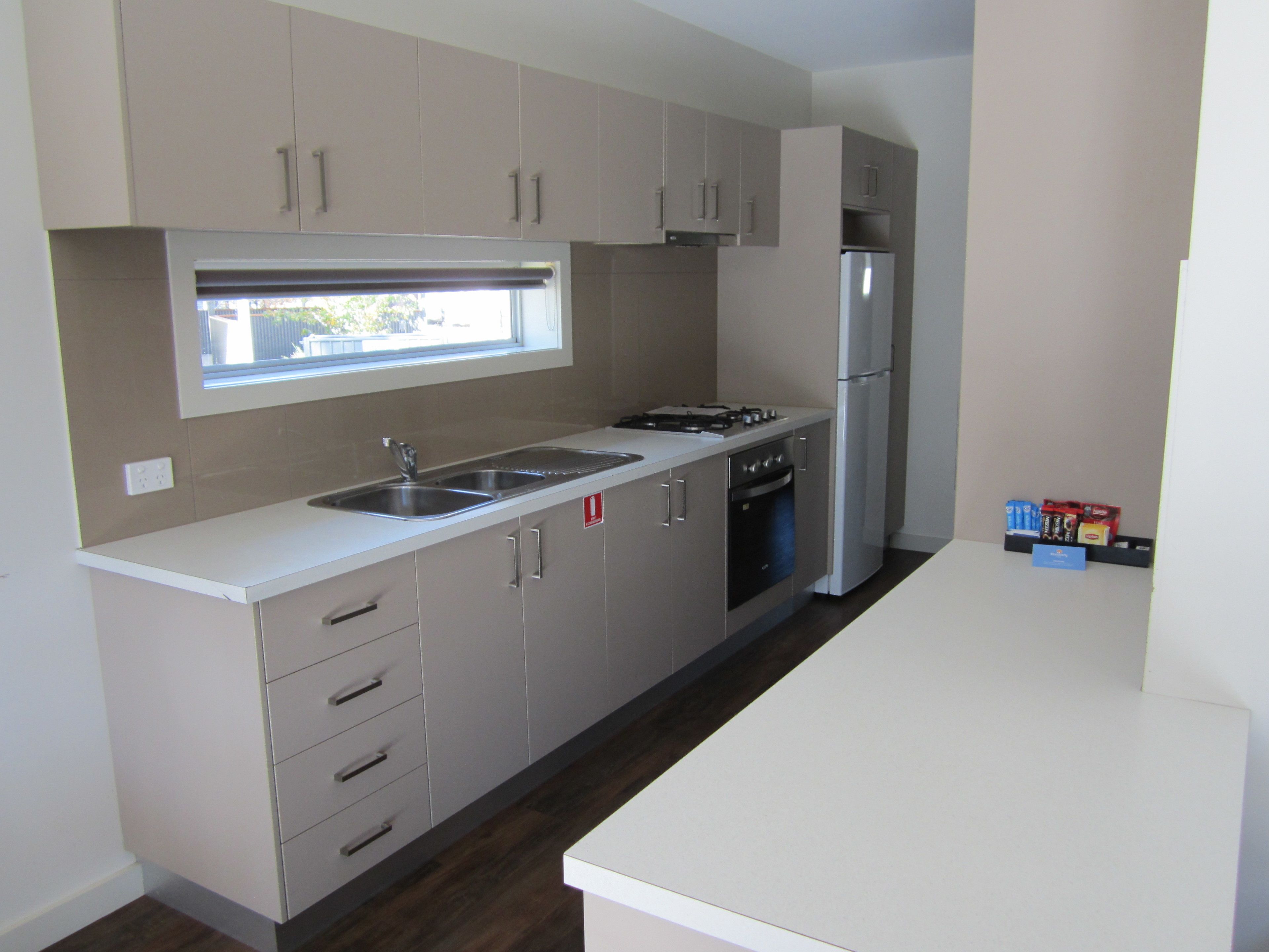 A modern kitchen with stainless steel appliances, a window above the sink, and a countertop with a few items.