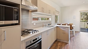 A modern kitchen with stainless steel appliances, a built-in oven, and a large window overlooking a balcony.