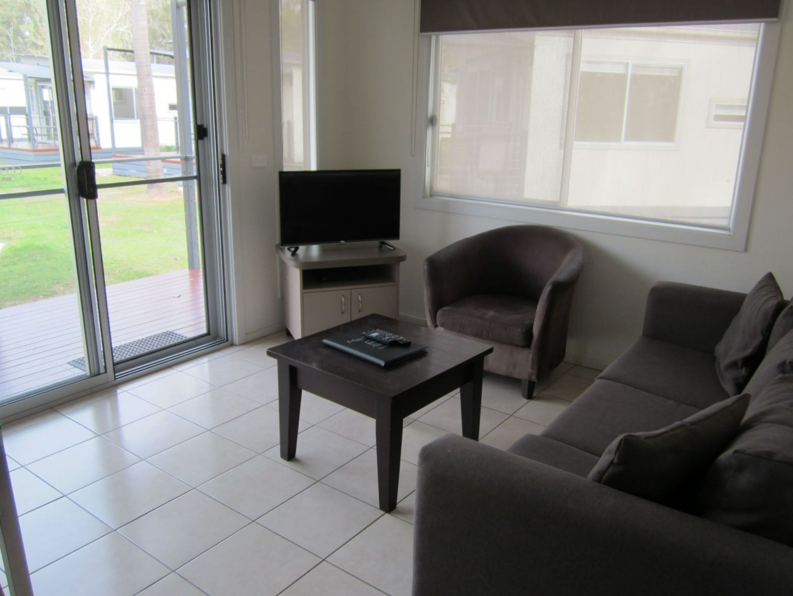 Una sala de estar con televisor, sofá, sillón y una mesa de centro.