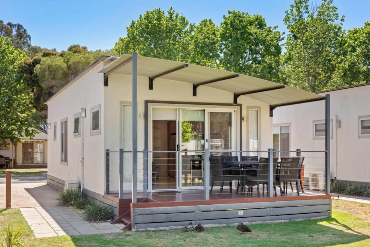 A single-story mobile home with a covered patio area and a sliding glass door entrance.