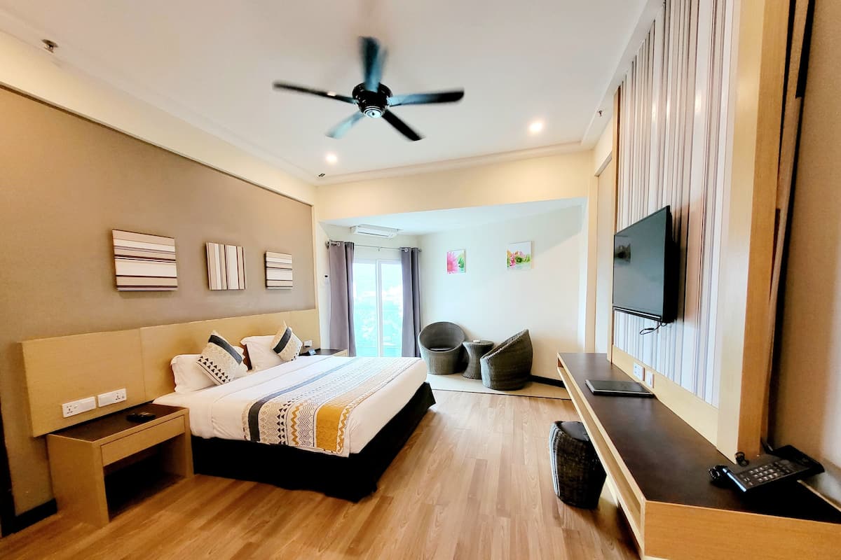 A modern hotel room with a bed, bedside table, desk, chair, and a ceiling fan.