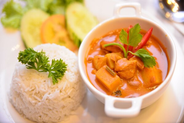 A bowl of curry with rice and vegetables.
